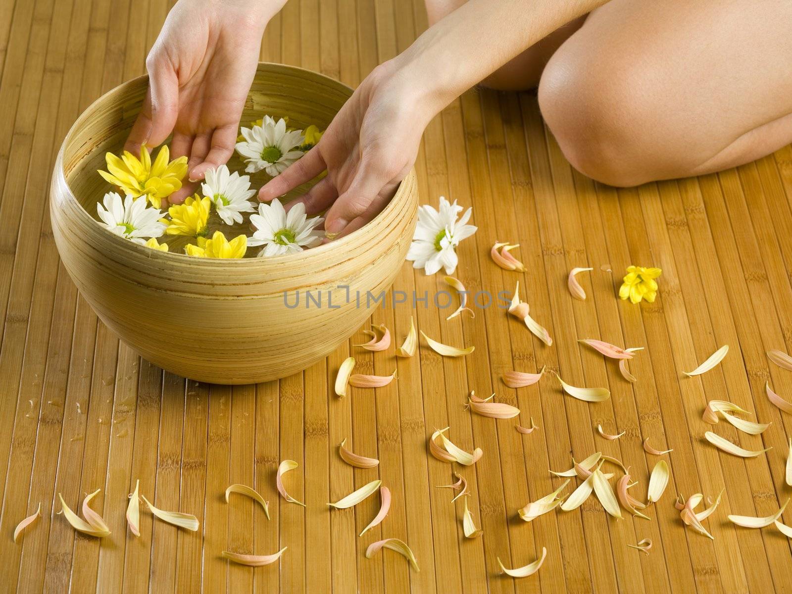 hands near a basin with flowers and water
