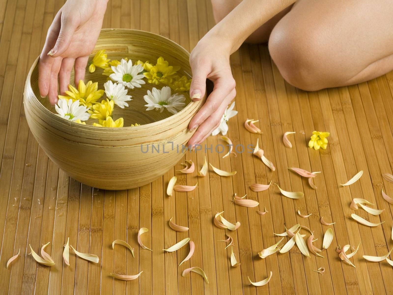 hands near a basin with flowers and water