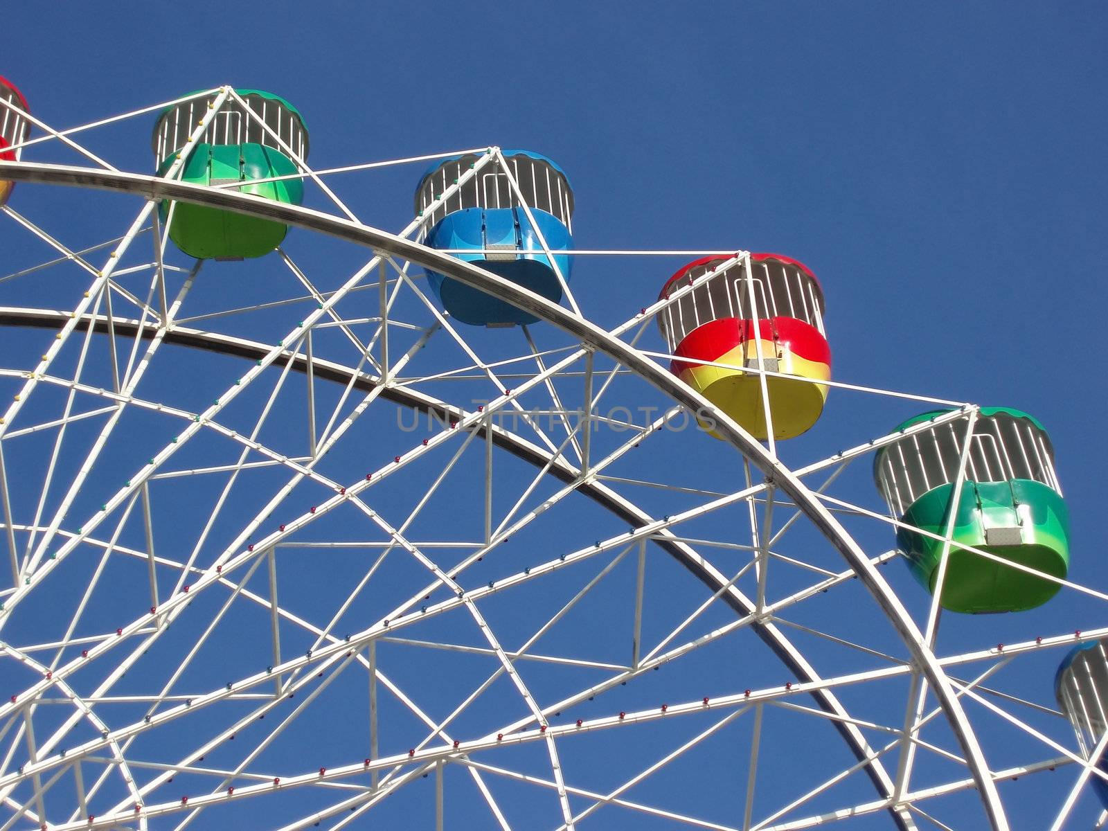 a colourful fairground wheel against a blue sky