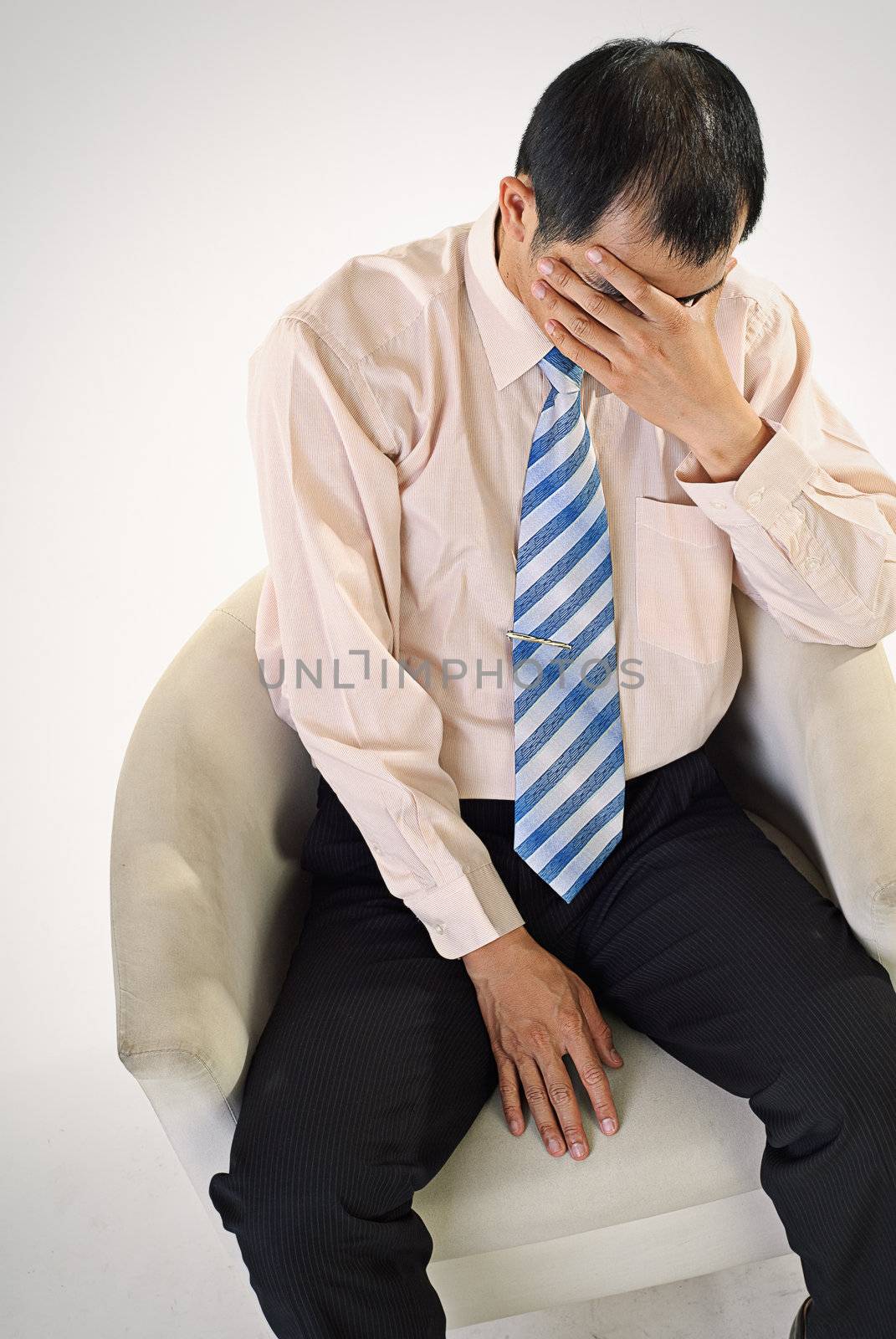 Sad business man sit on chair and cover face by hand.