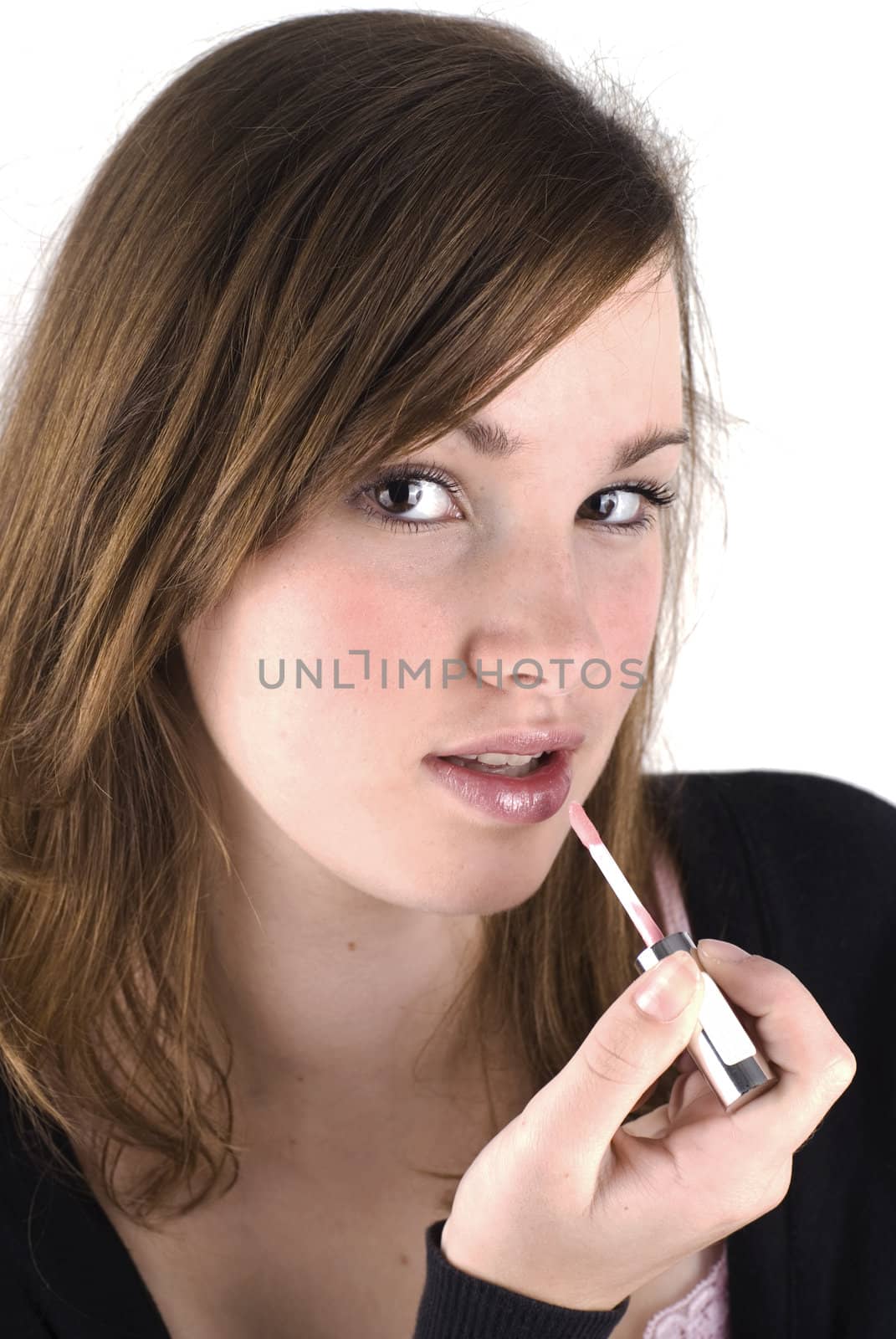 Beautiful teenage girl is putting up lipgloss, isolated on a white background.