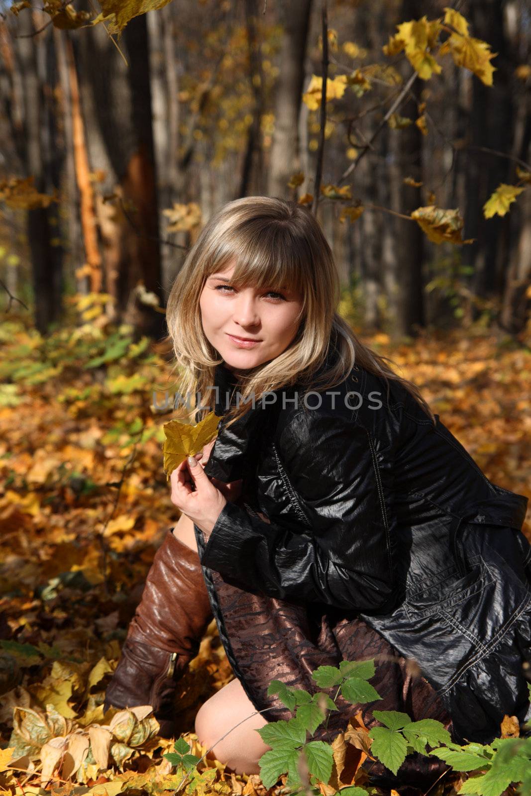 happy young girl with yellow leaf on autumn background