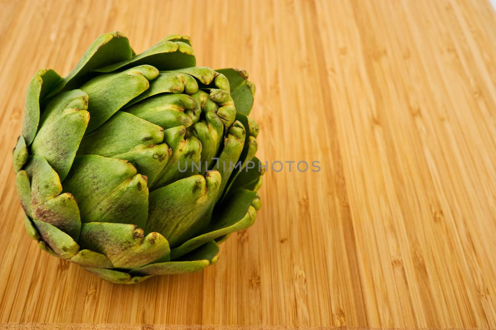 Image of an artichoke on wooden cutting board