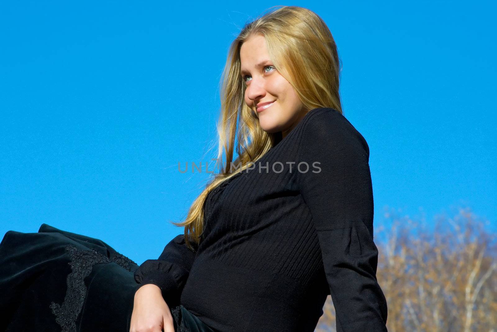 Portrait of the beautiful young girl against blue sky
