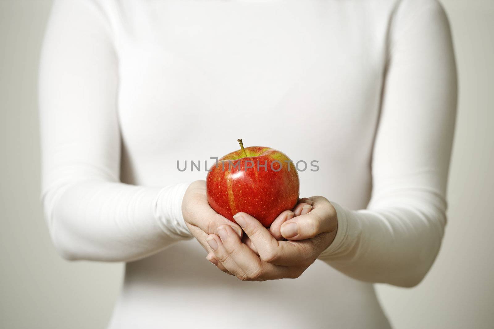 Image of a female holding a ripe red apple.