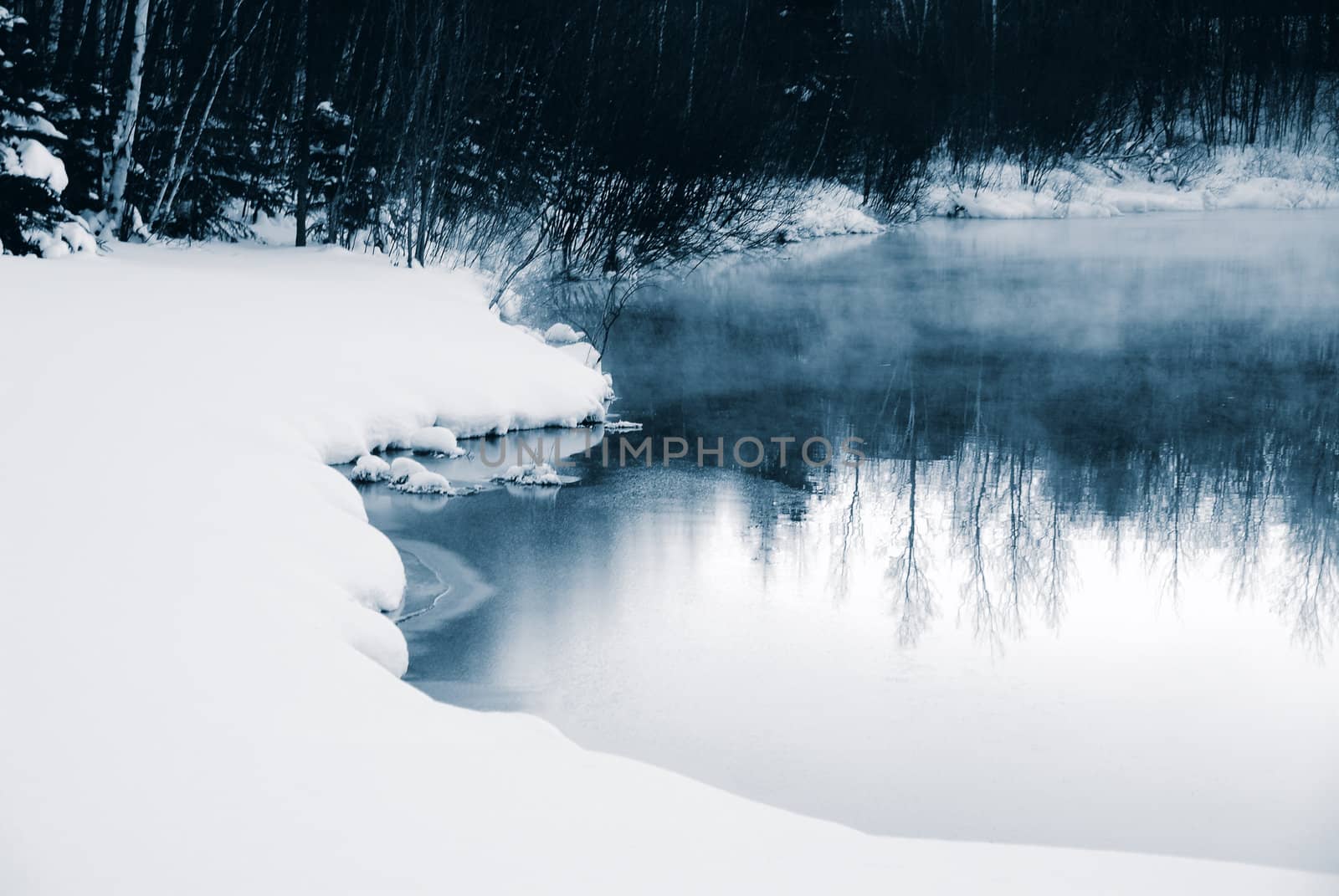 A winter landscape showing a foggy river in blue tones