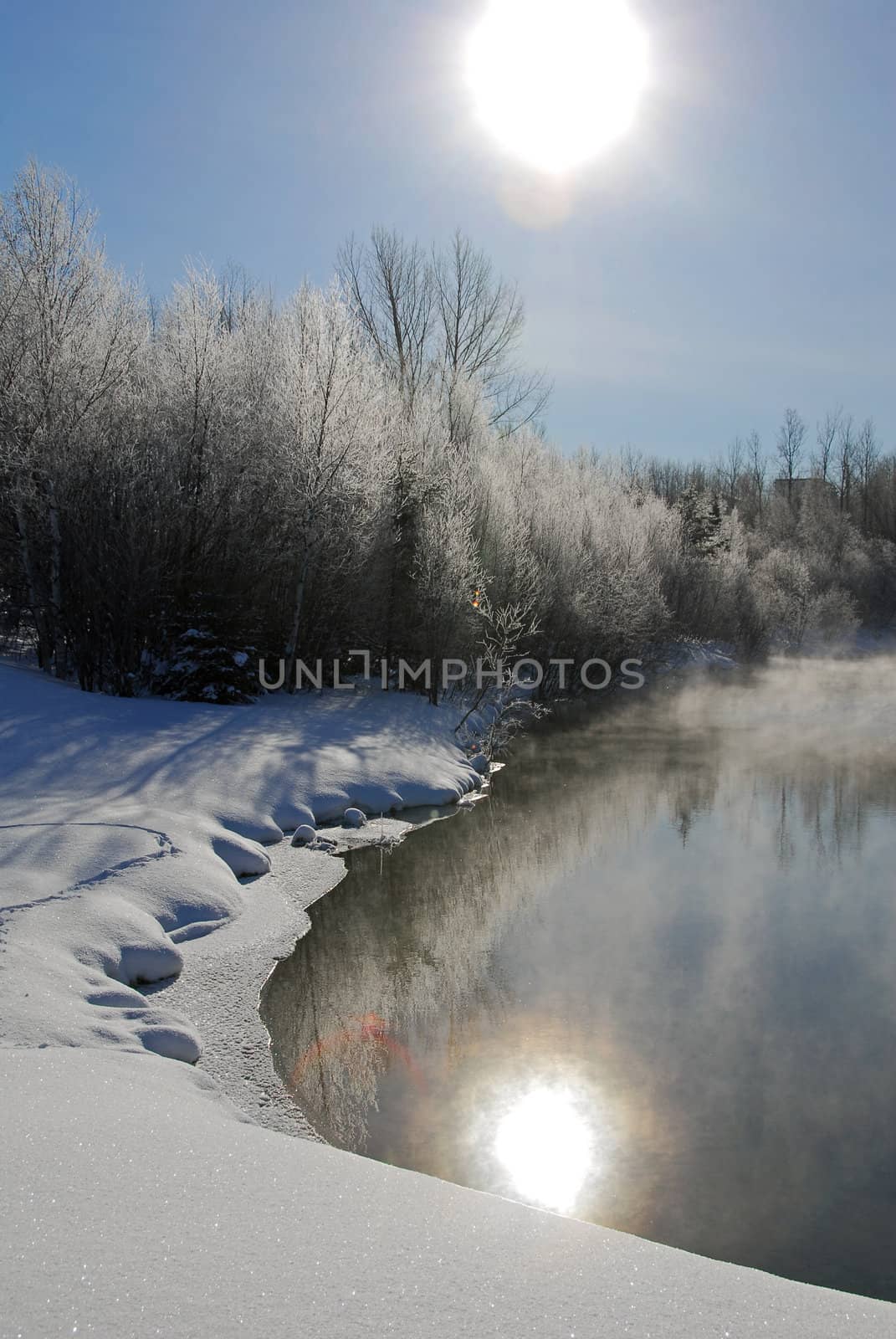 A winter landscape showing a foggy river on a cold day