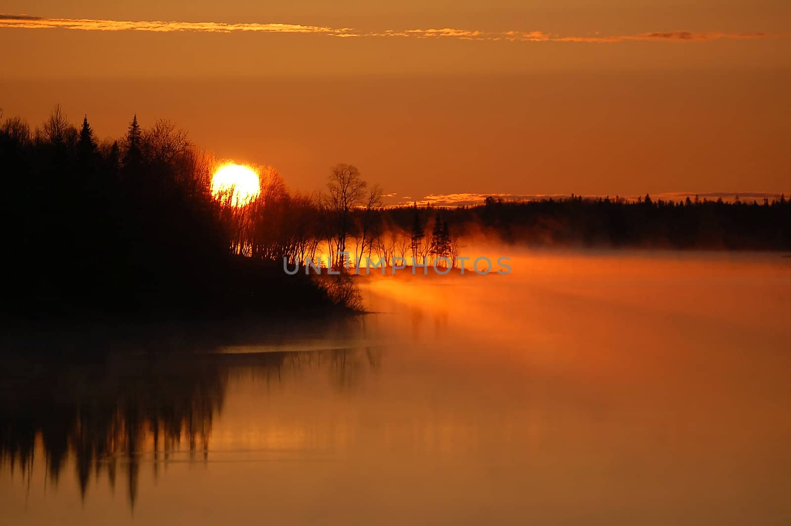 A colorful sunrise over a foggy Northern River