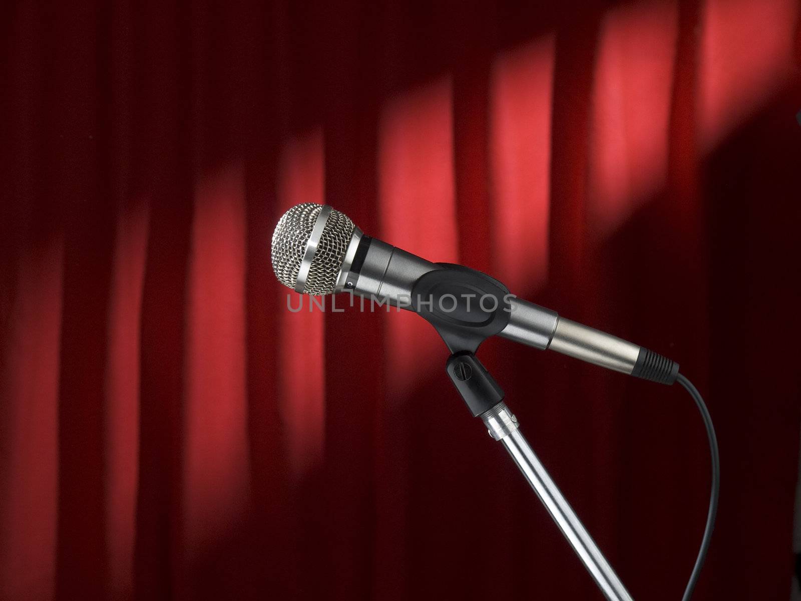 A microphone on stage over a red background.