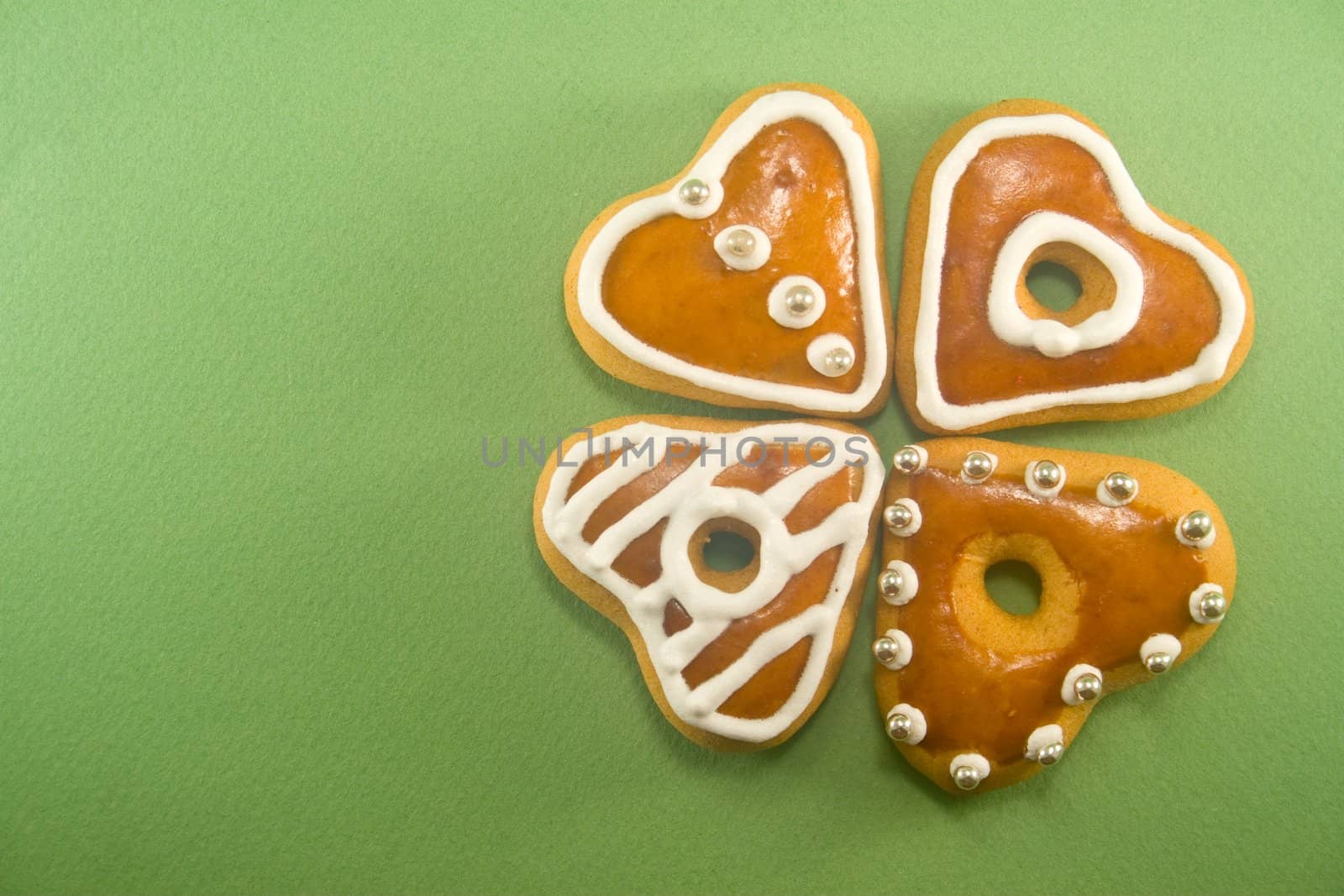 Decorated Christmas cookies in clover formation against green background ad space on left