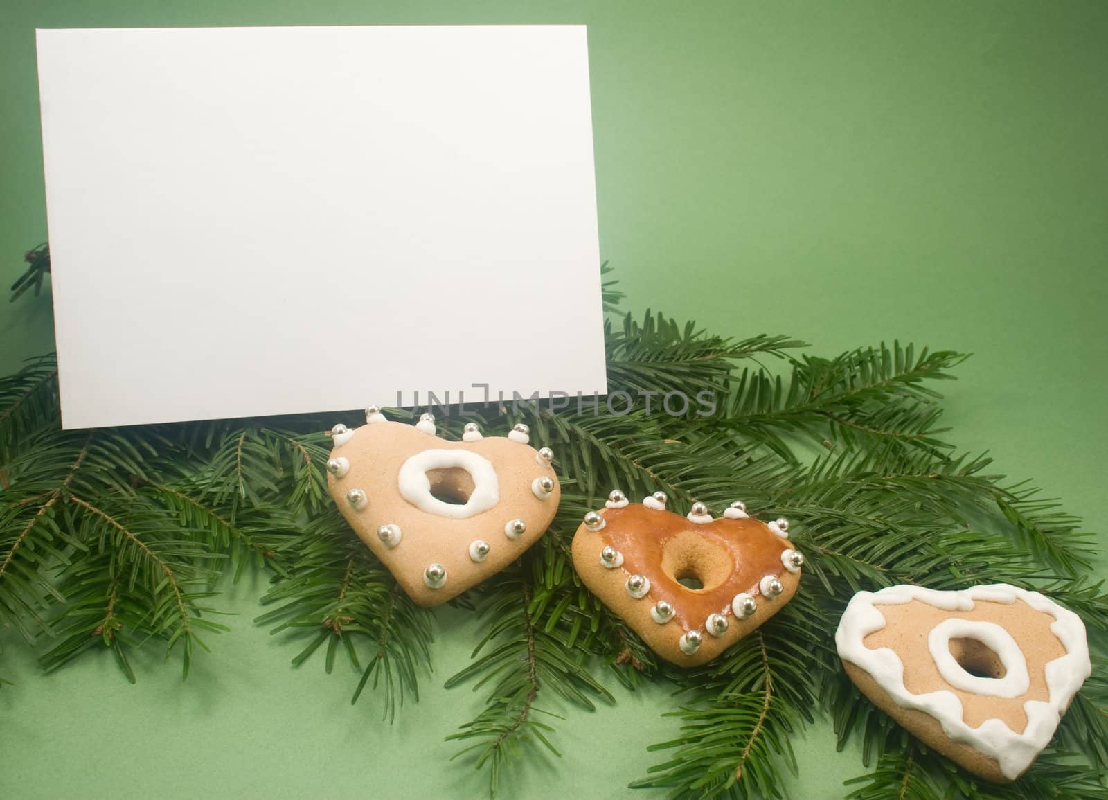 Three heart gingerbread cookies on fir branch with white note