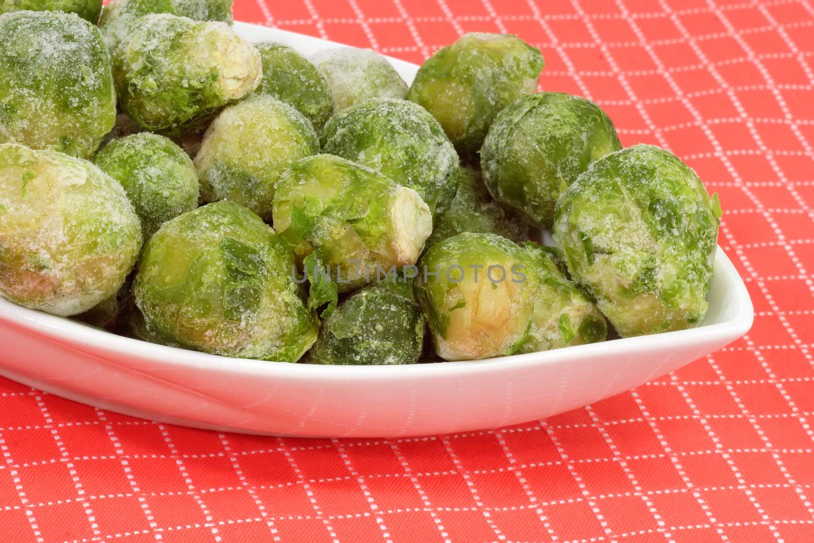 Frozen Brussels sprouts in a bowl on red background