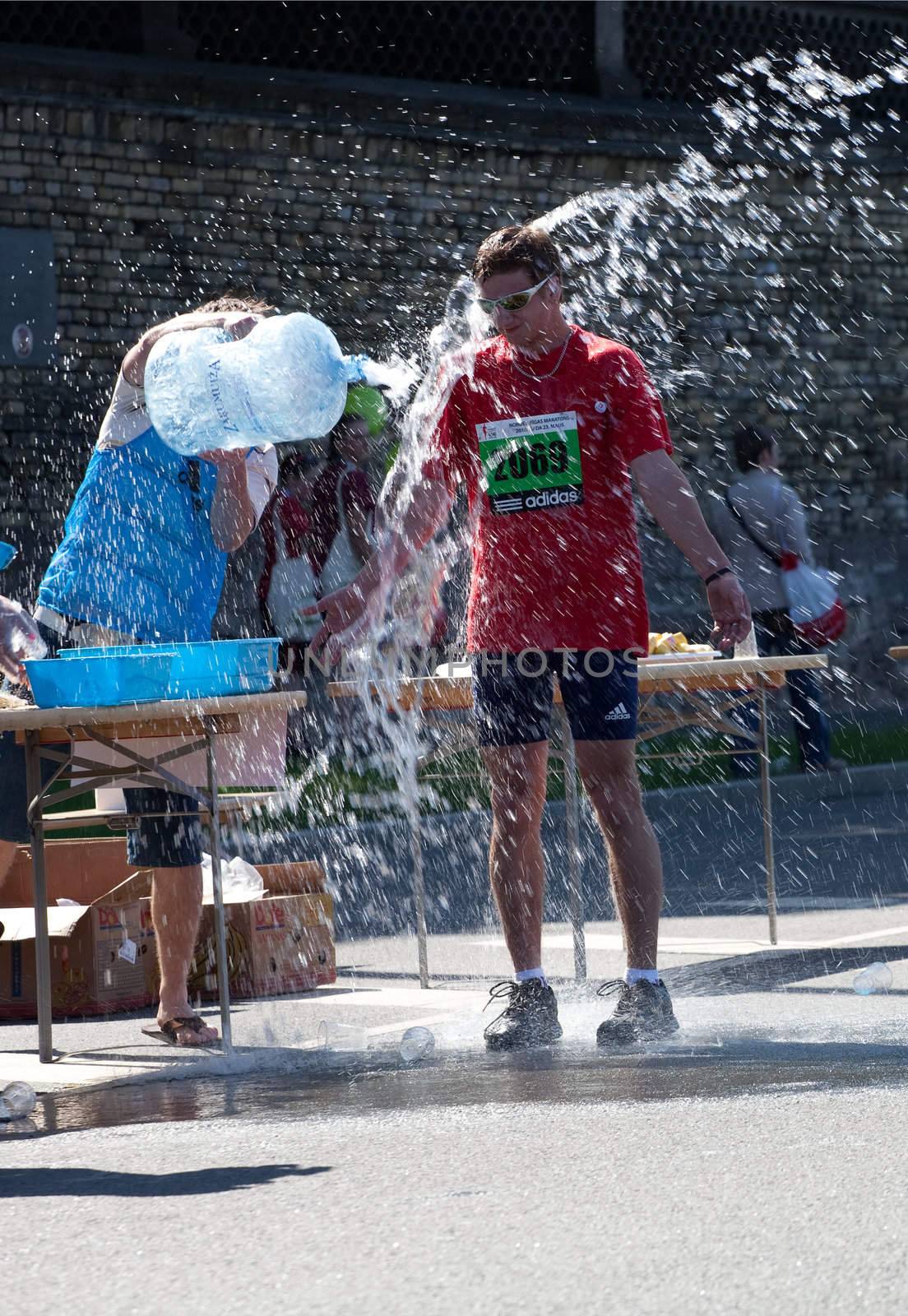 RIGA, LATVIA - MAY 23: Runner of Riga International Marathon take refreshing water shower on May 23, 2010 in Riga.