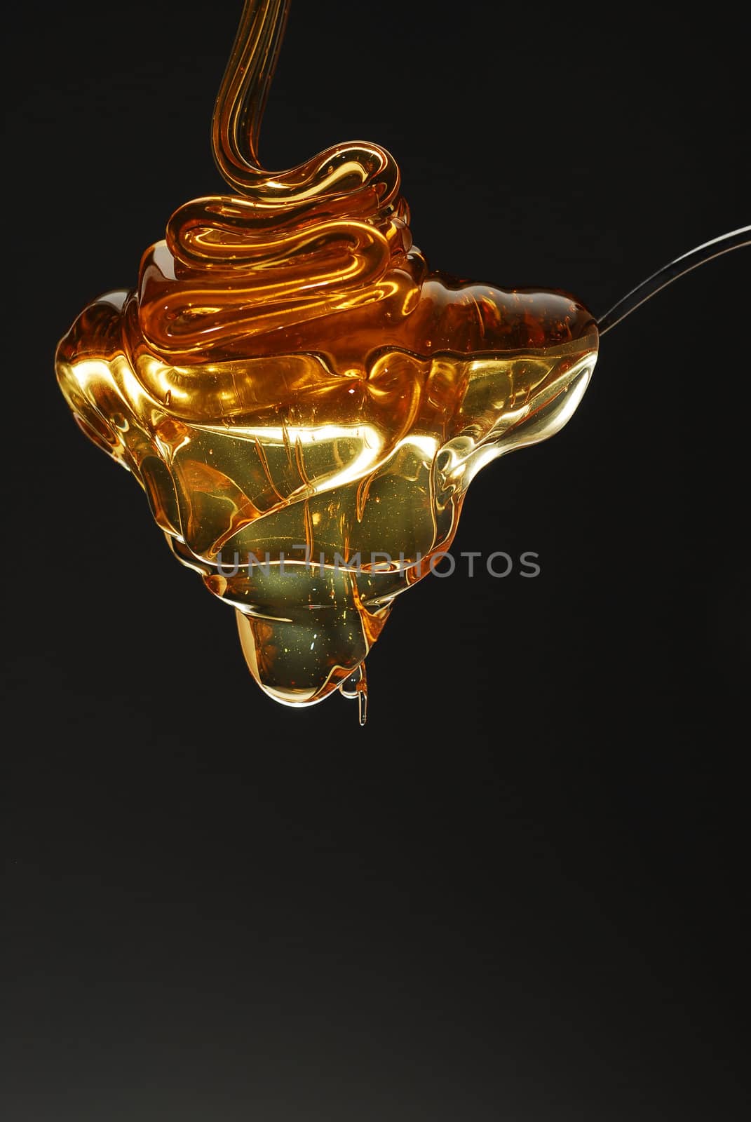 Golden honey spilling over the spoon stock photo