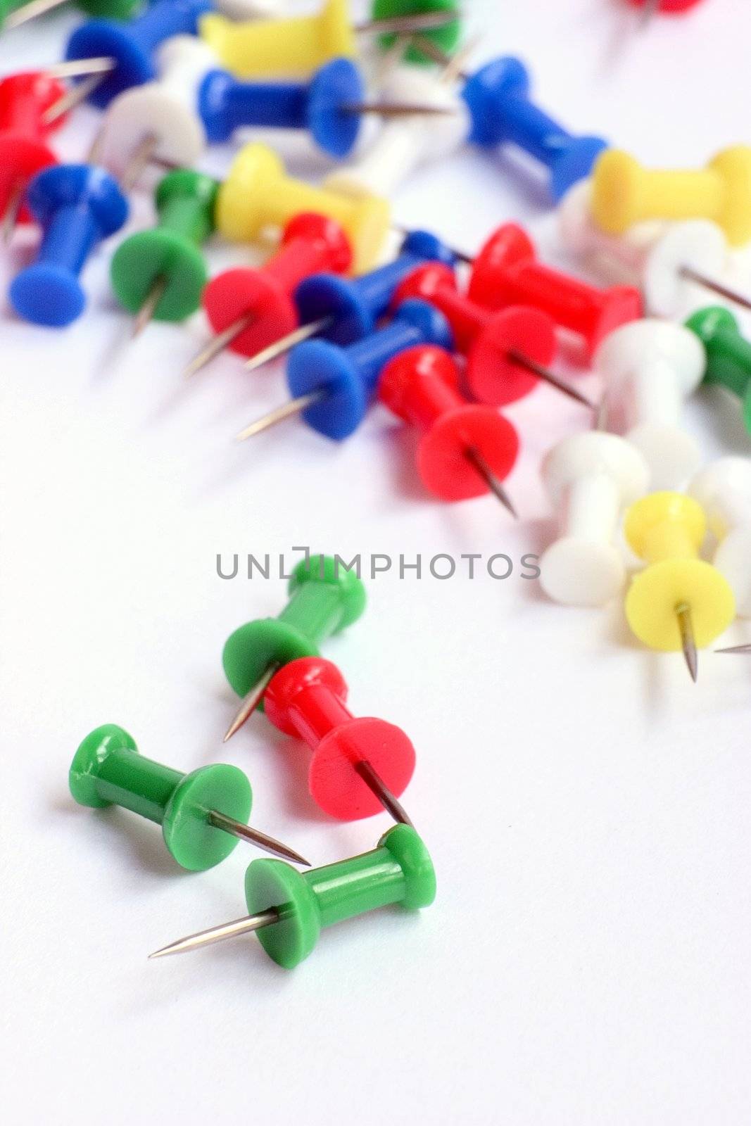 Multicolored push pins on bright background