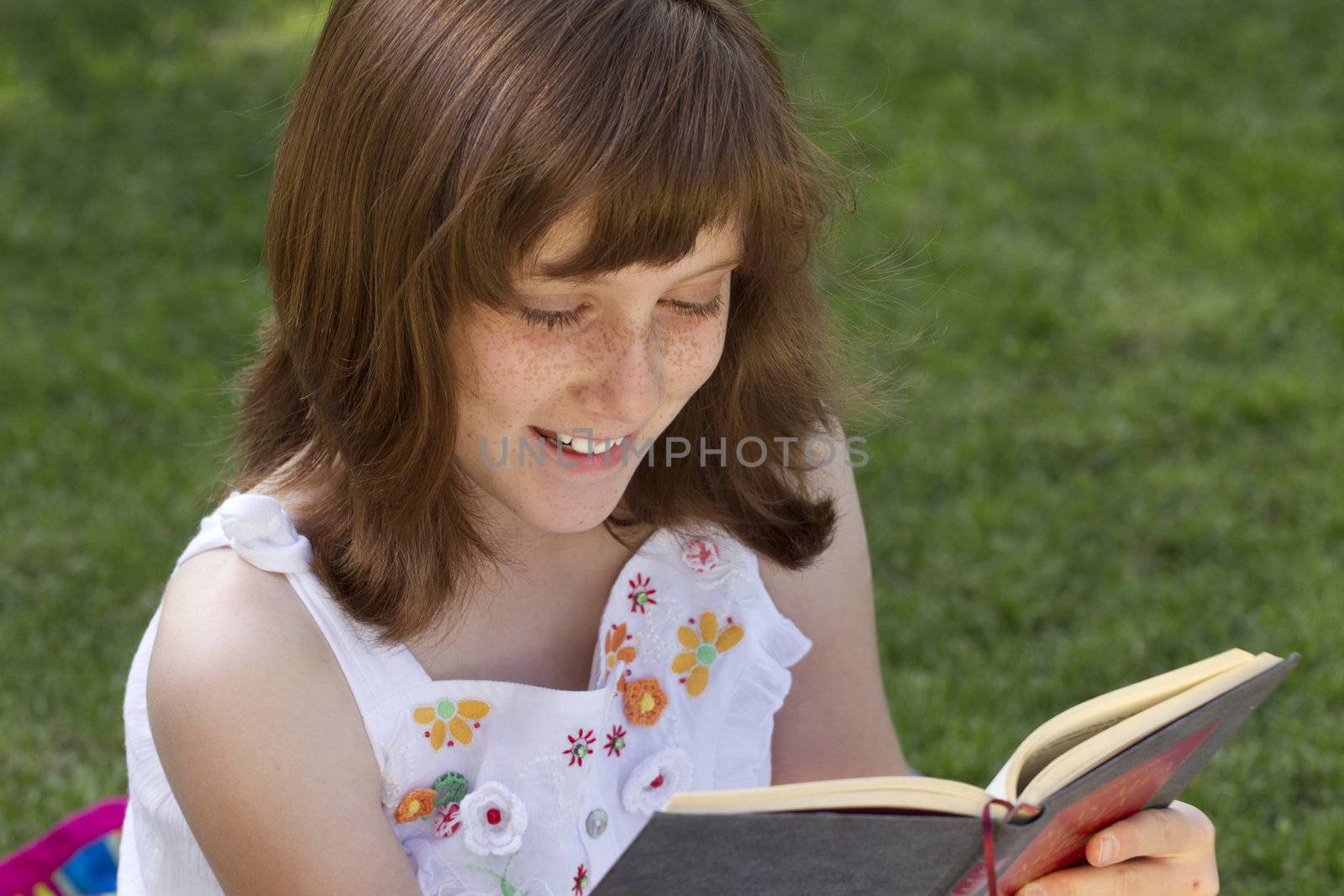 Young beautiful girl reading a book outdoor by FernandoCortes