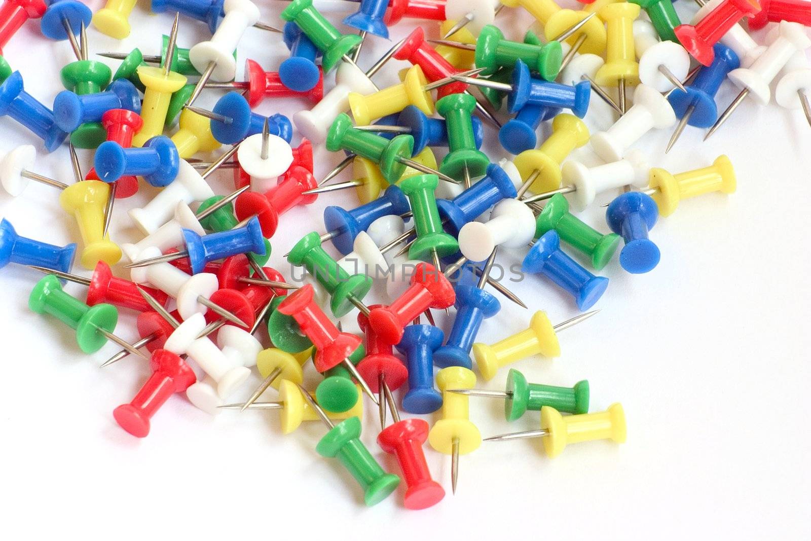 Multicolored push pins on bright background