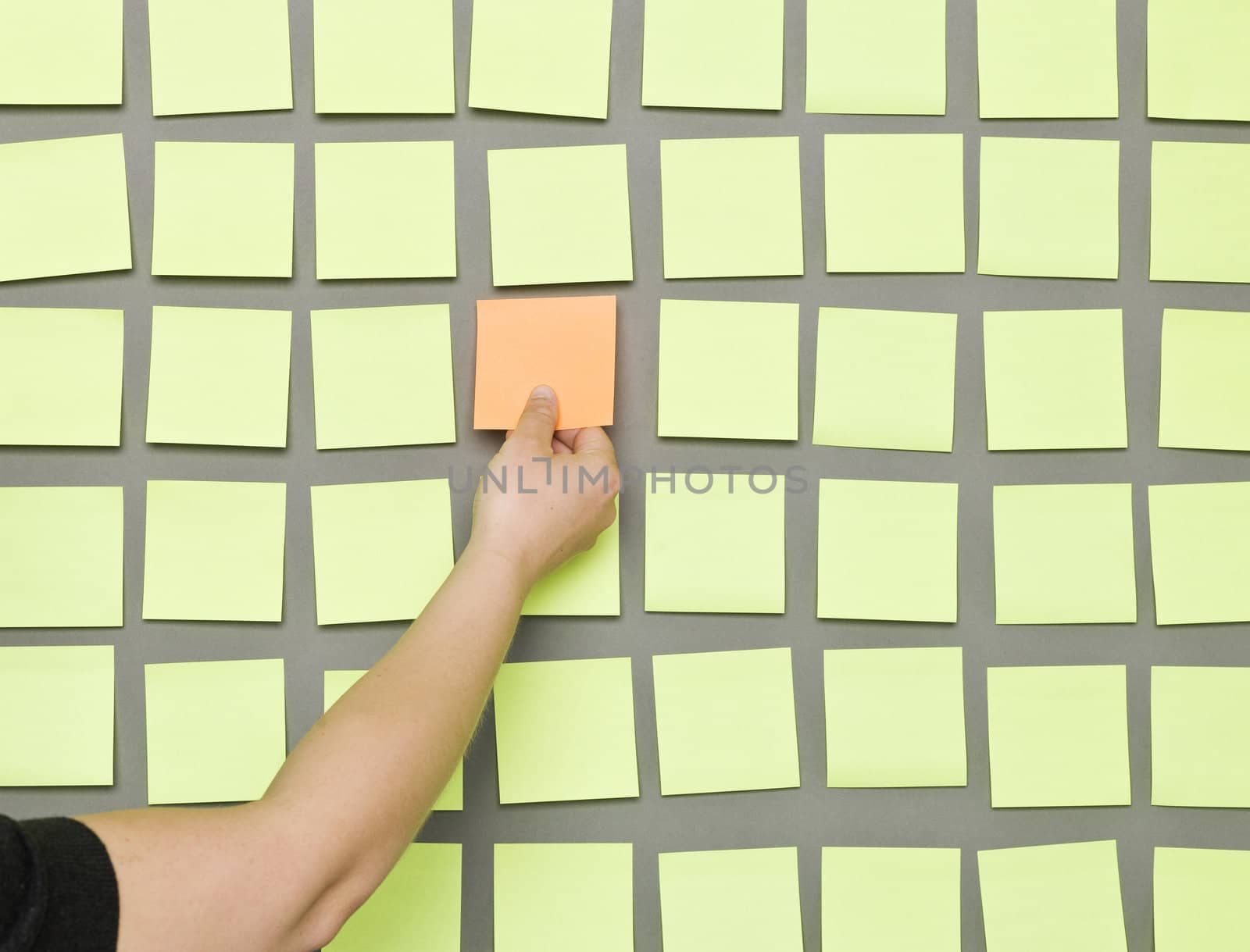 Hand taking an Adhesive Note from a wall