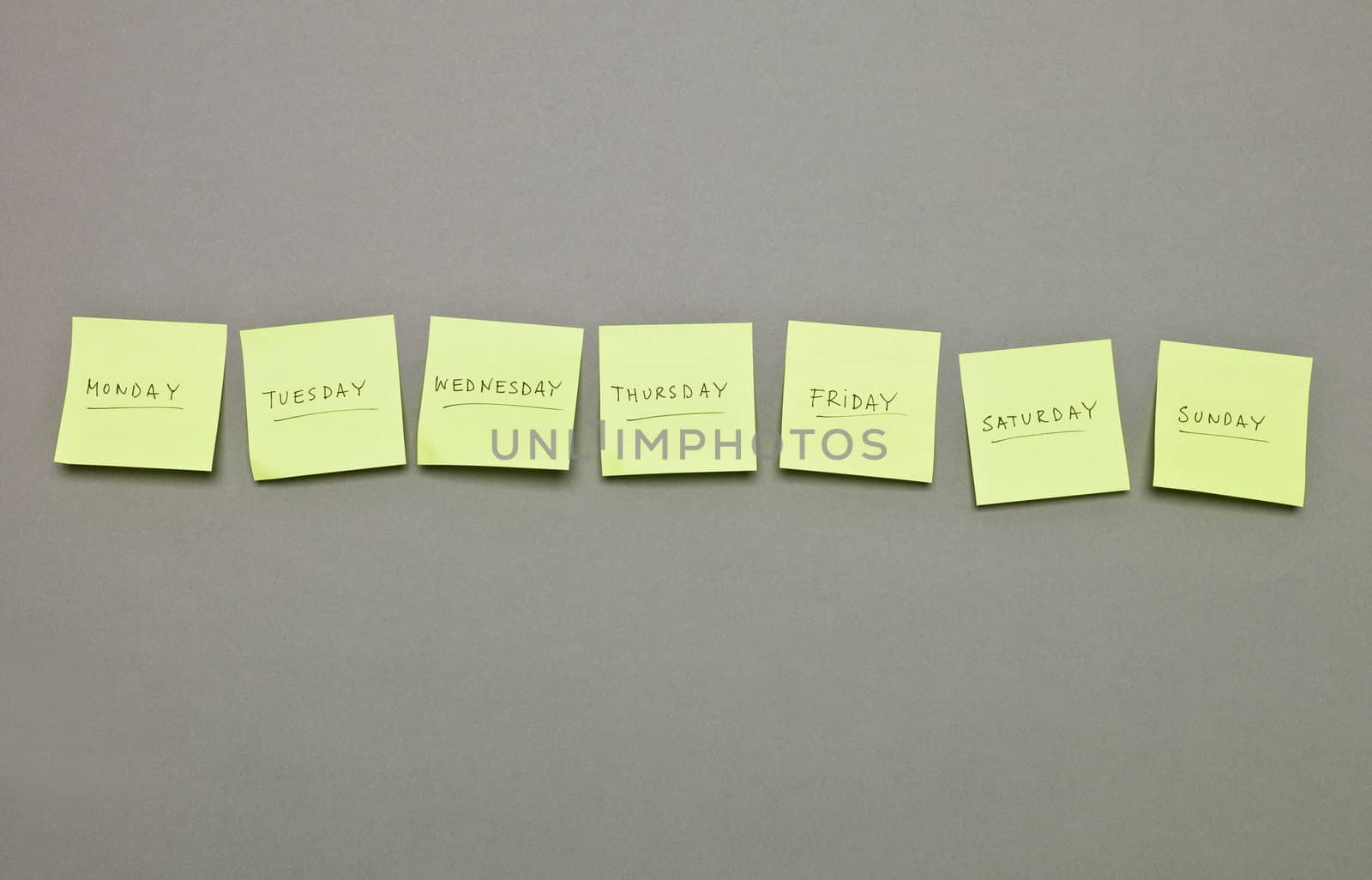 Adhesive Notes with the weekdays in a row on grey background