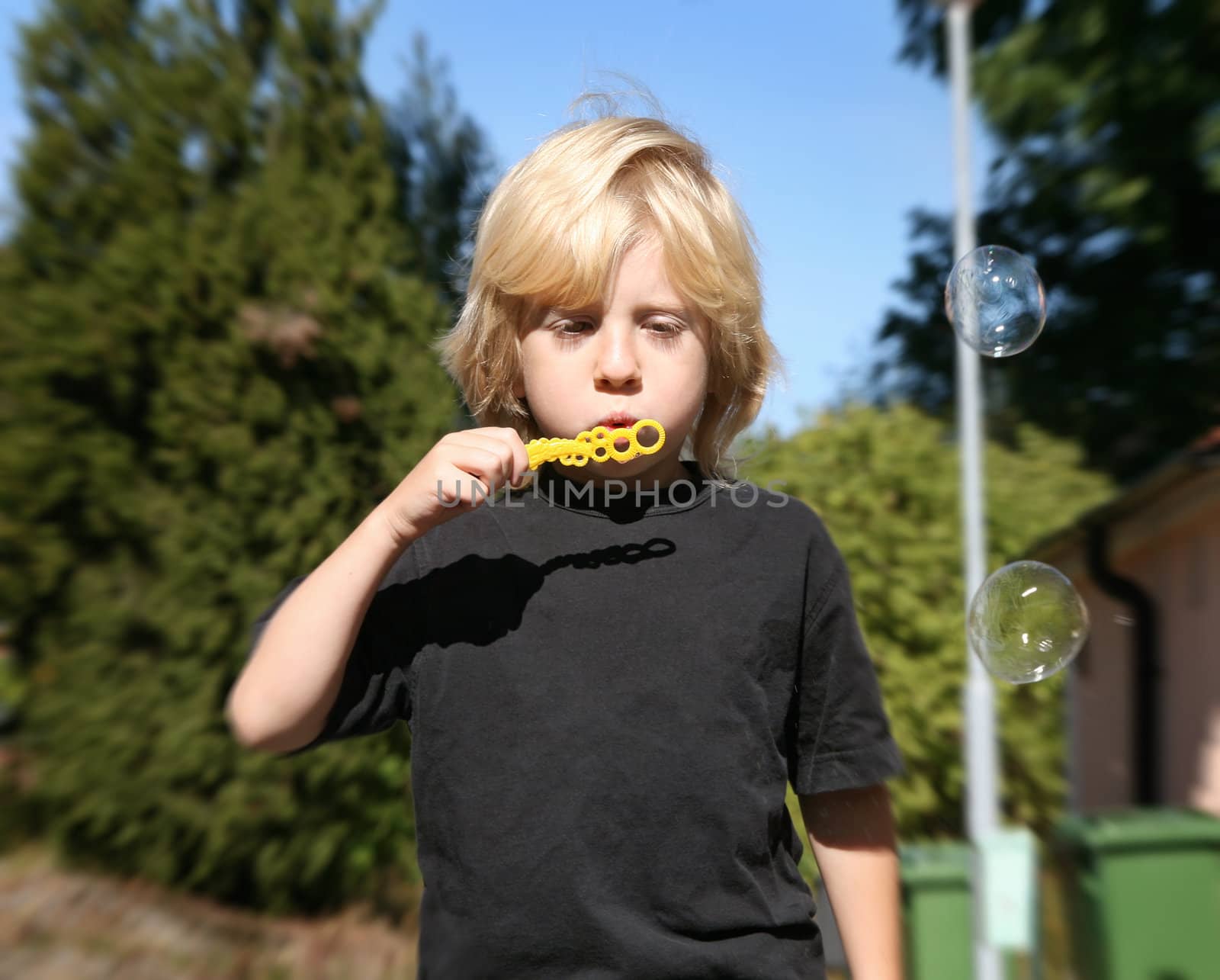 young boy blowing soap bubbles outdoors