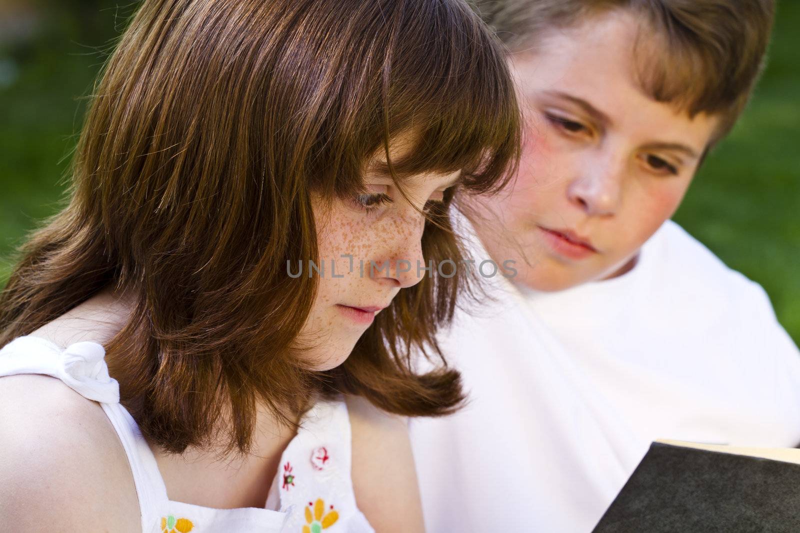 Portrait of cute kids reading books in natural environment