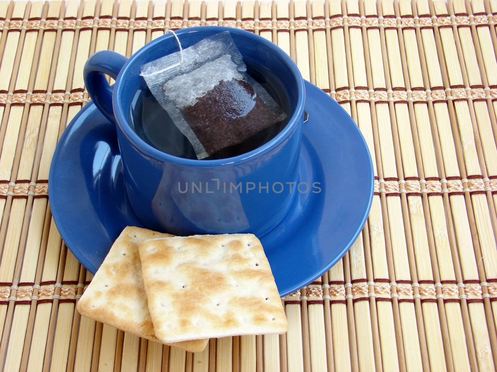 Close up of a cup of tea with 2 crackers.                        