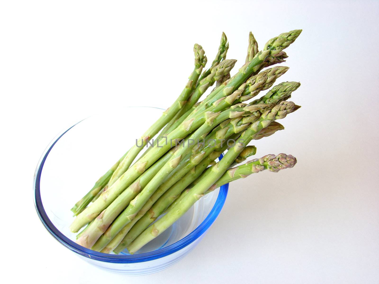 Bunch of asparagus in a bowl ready to cook, on white background