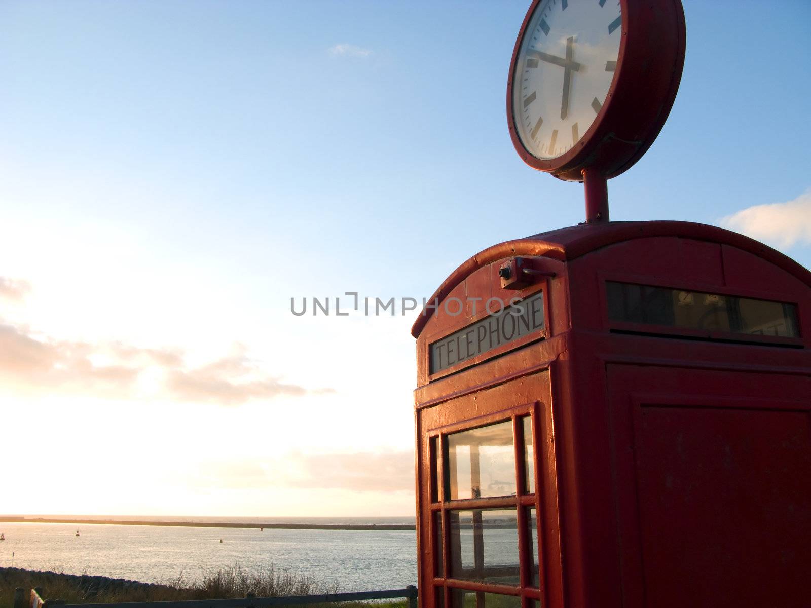 Red telephone box with view at sea