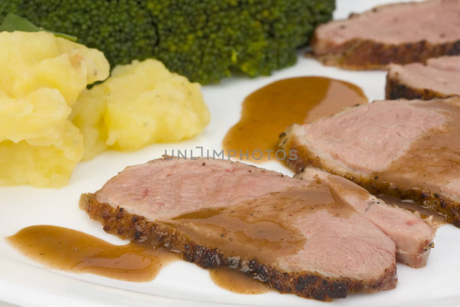 slices of a roasted duck fillet on a white plate