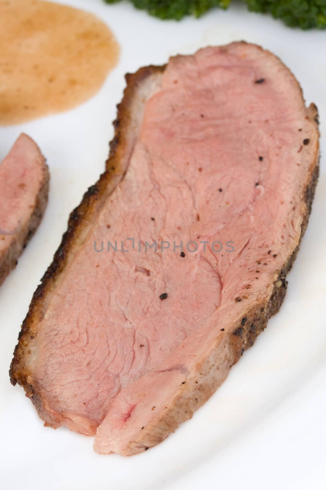 slices of a roasted duck fillet on a white plate by bernjuer