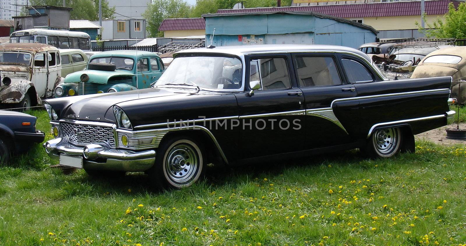 Black classic car among the crashed autos