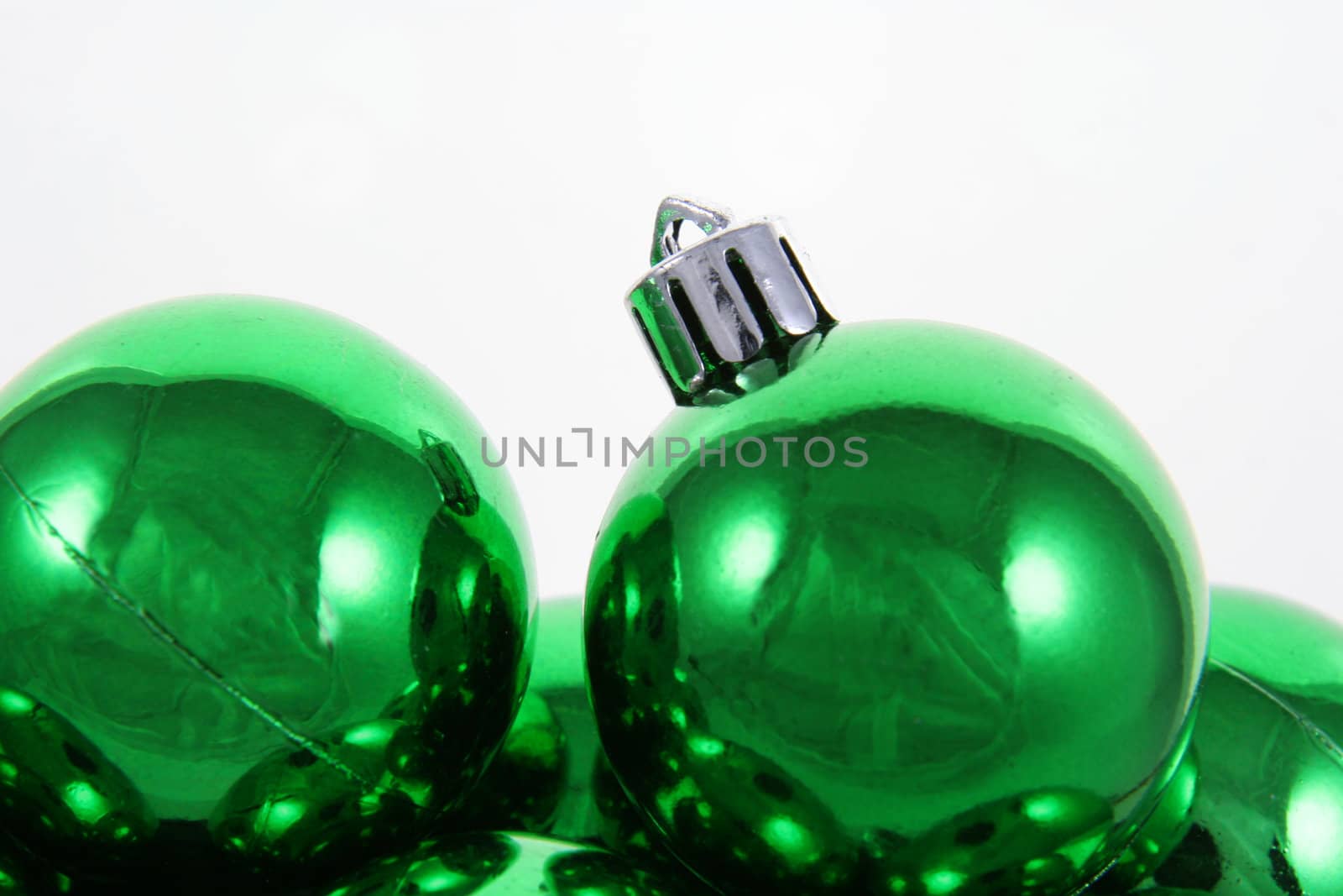 A bunch of green Christmas baubles against a white background.
