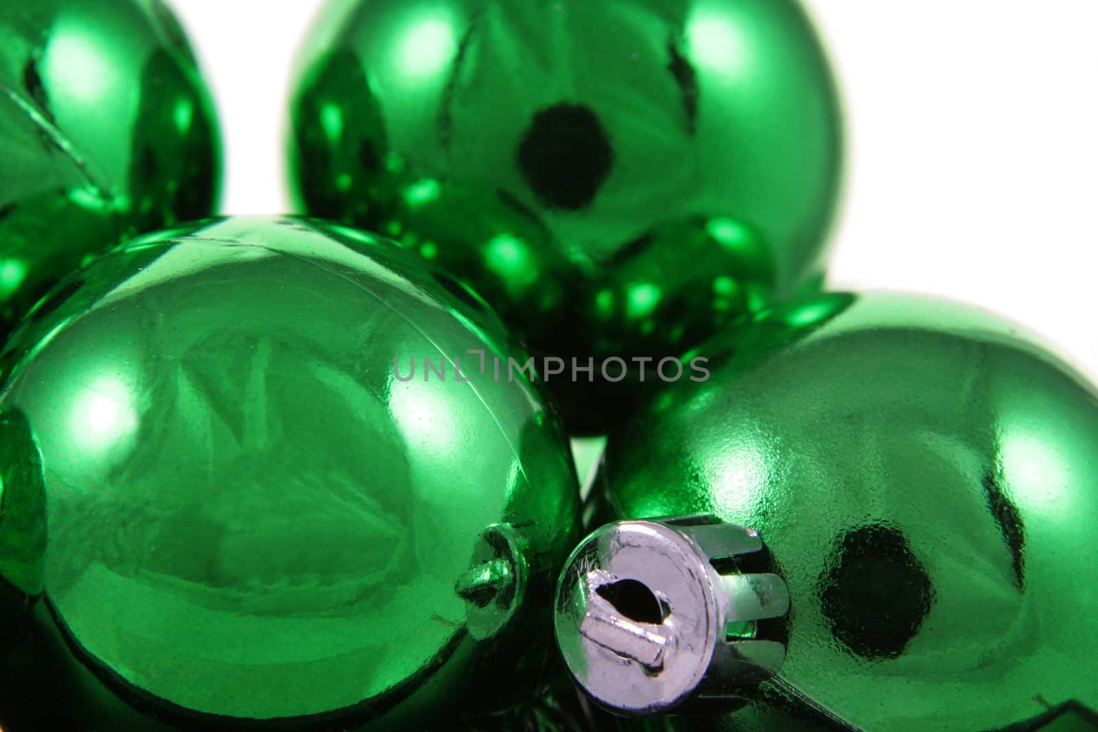 A bunch of green Christmas baubles against a white background.
