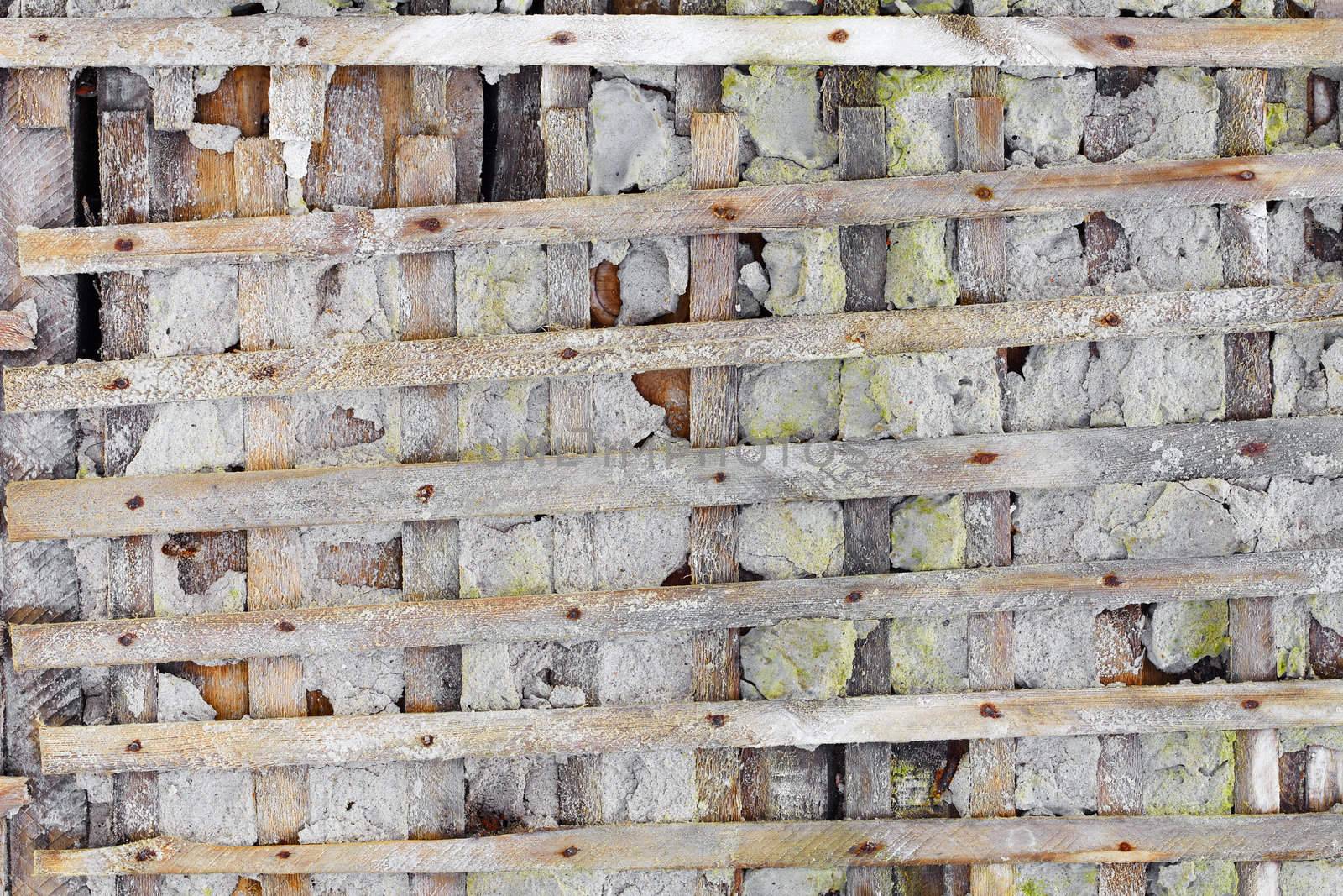 Concrete ruined wall, reinforced wooden lattice - background