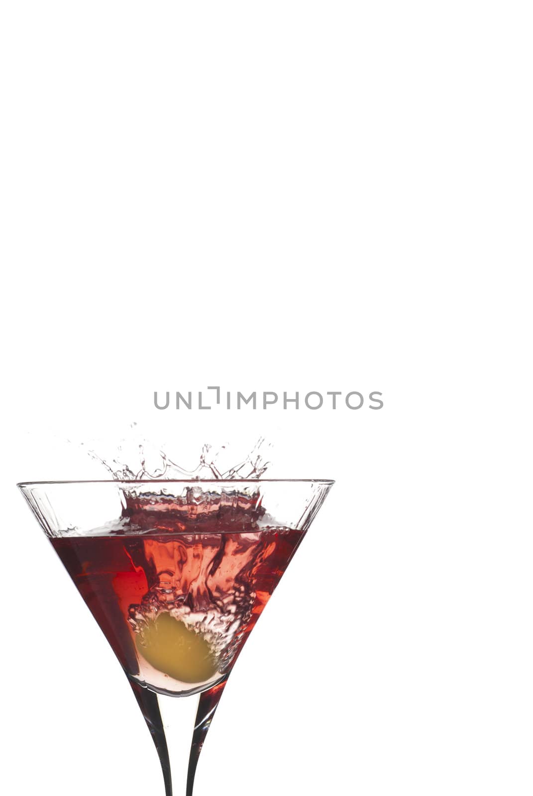 Cocktail splash like crown with olive on red martini isolated on white