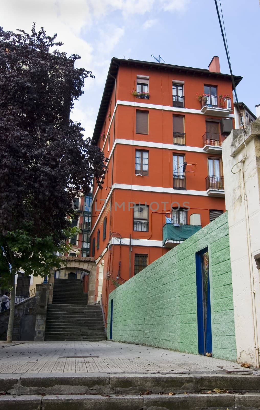 urban scenic of a green wall and a red building over a blue sky