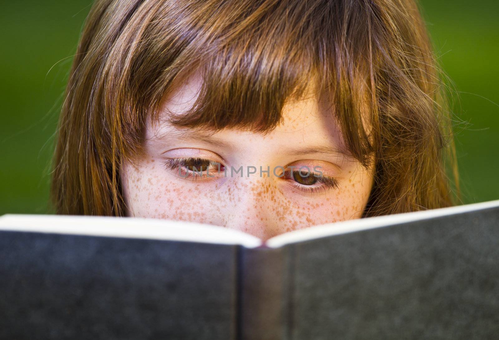 Young beautiful girl reading a book outdoor