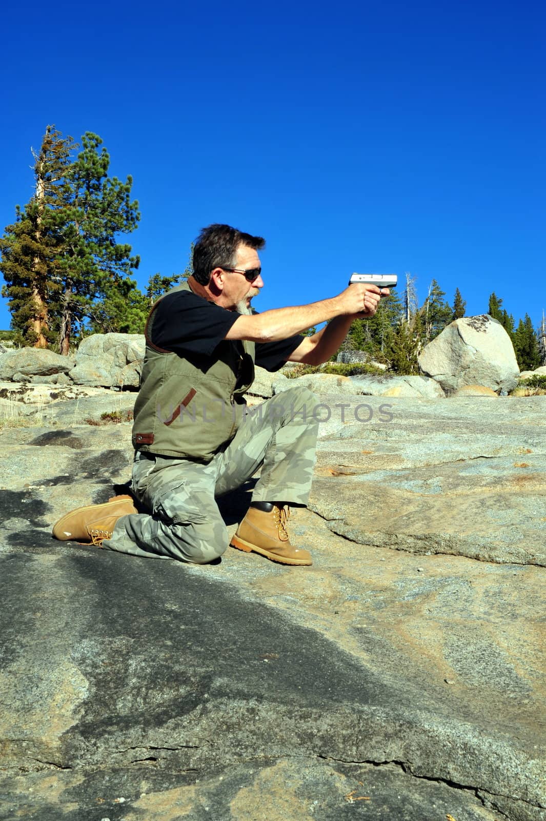 Man target shooting in a kneeling position with a semi automatic pistol