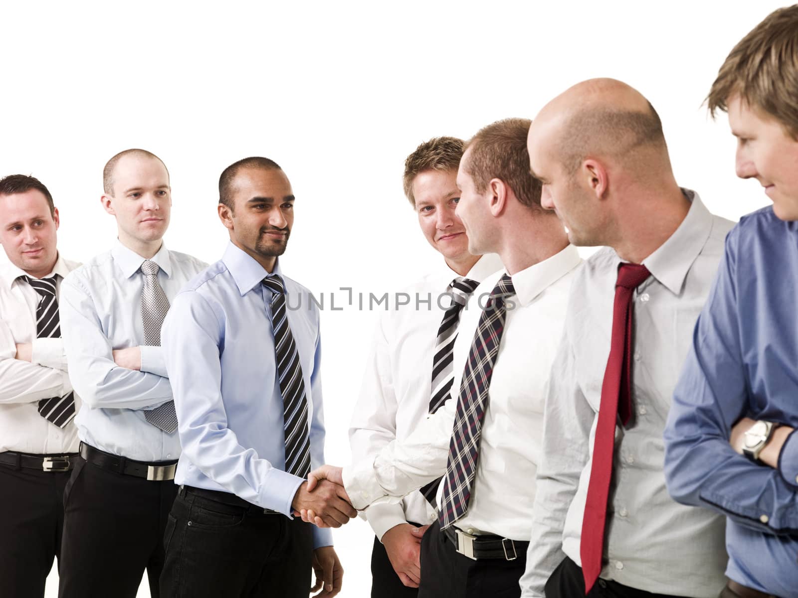 Businessmen shaking hands standing in a group of people