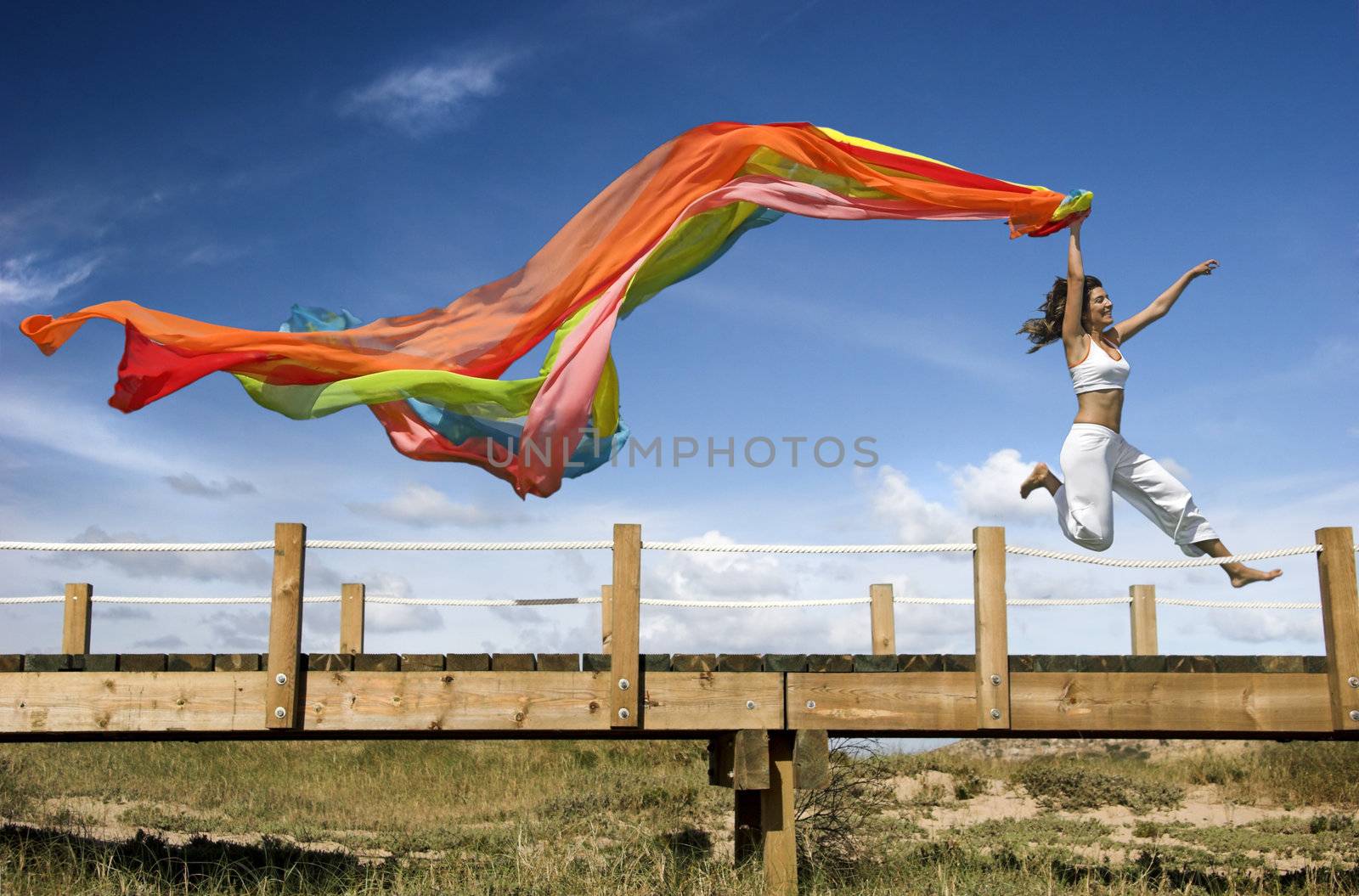 Young beautiful woman jumping with a scarf