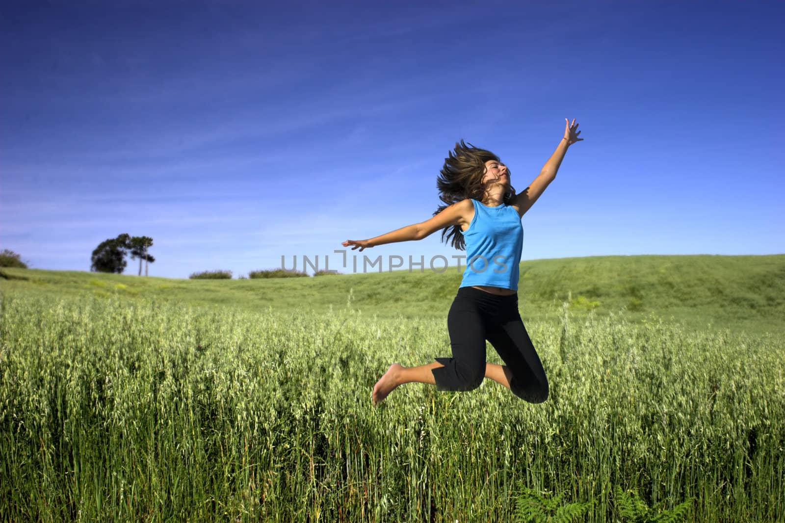 Young active woman jumping on a green field