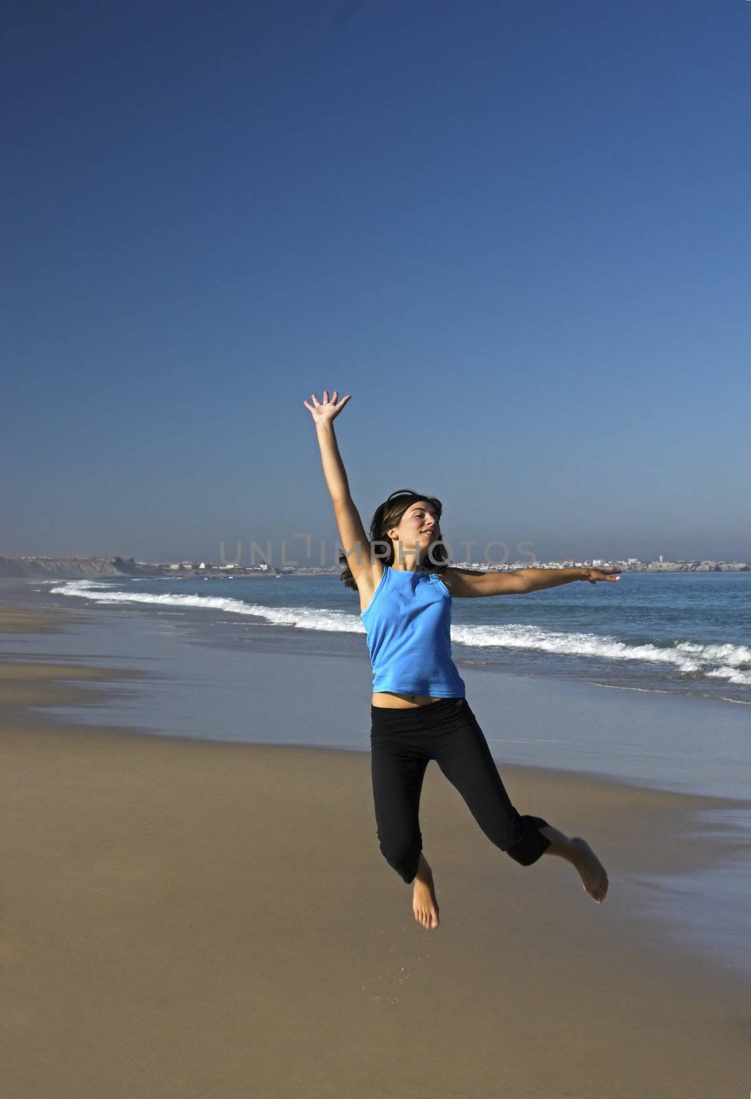 Young active woman jumping on the beach.