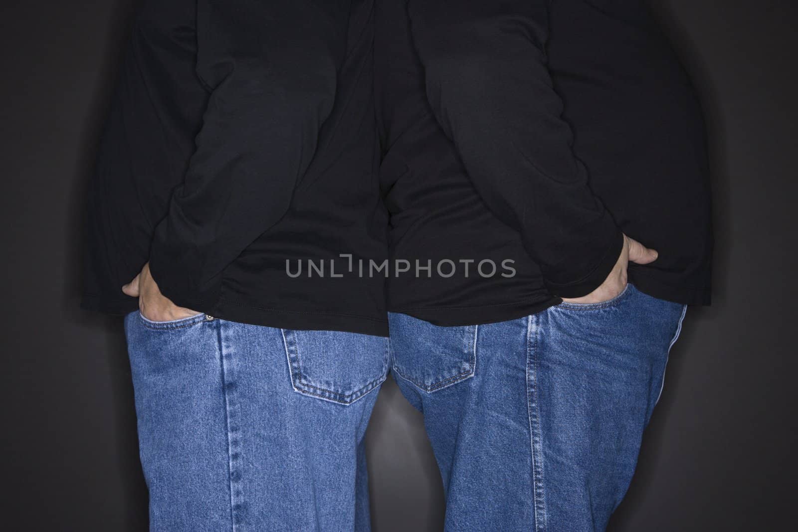 Bodies of Caucasian mid adult identical twin men standing back to back.