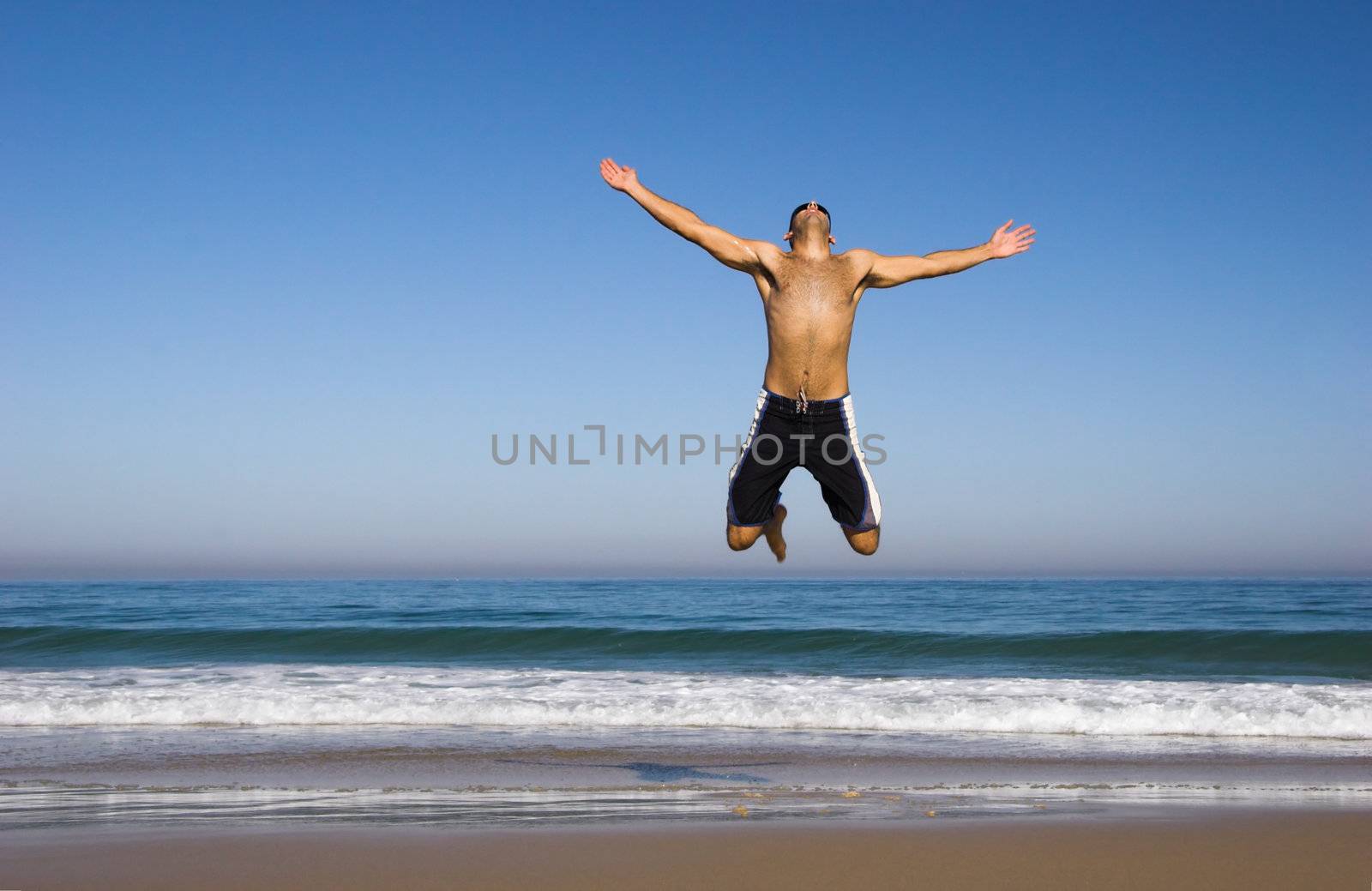 Man running and jumping on the beach by Iko