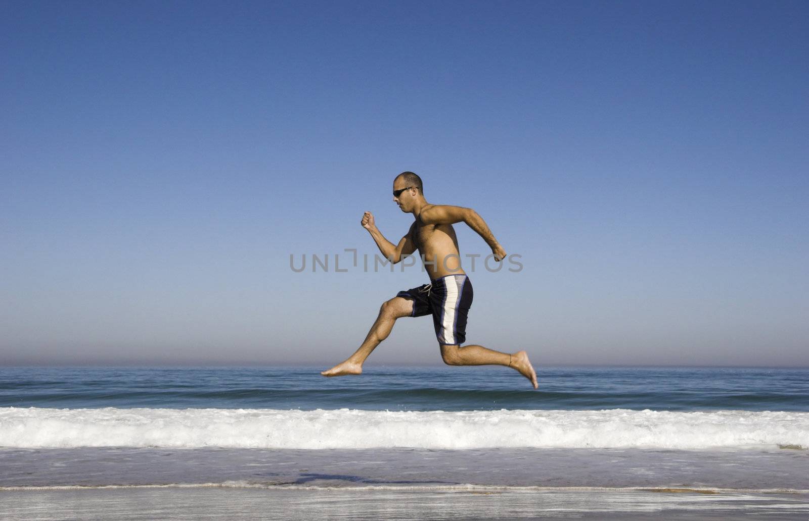 Man running and jumping on the beach by Iko