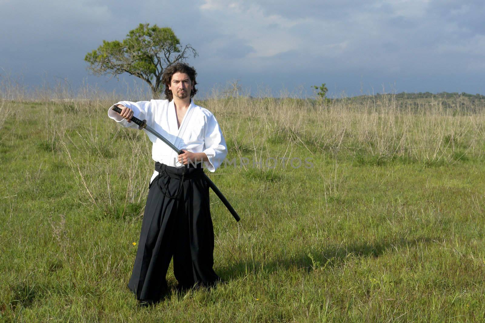 young aikido man with a sword, outdoors