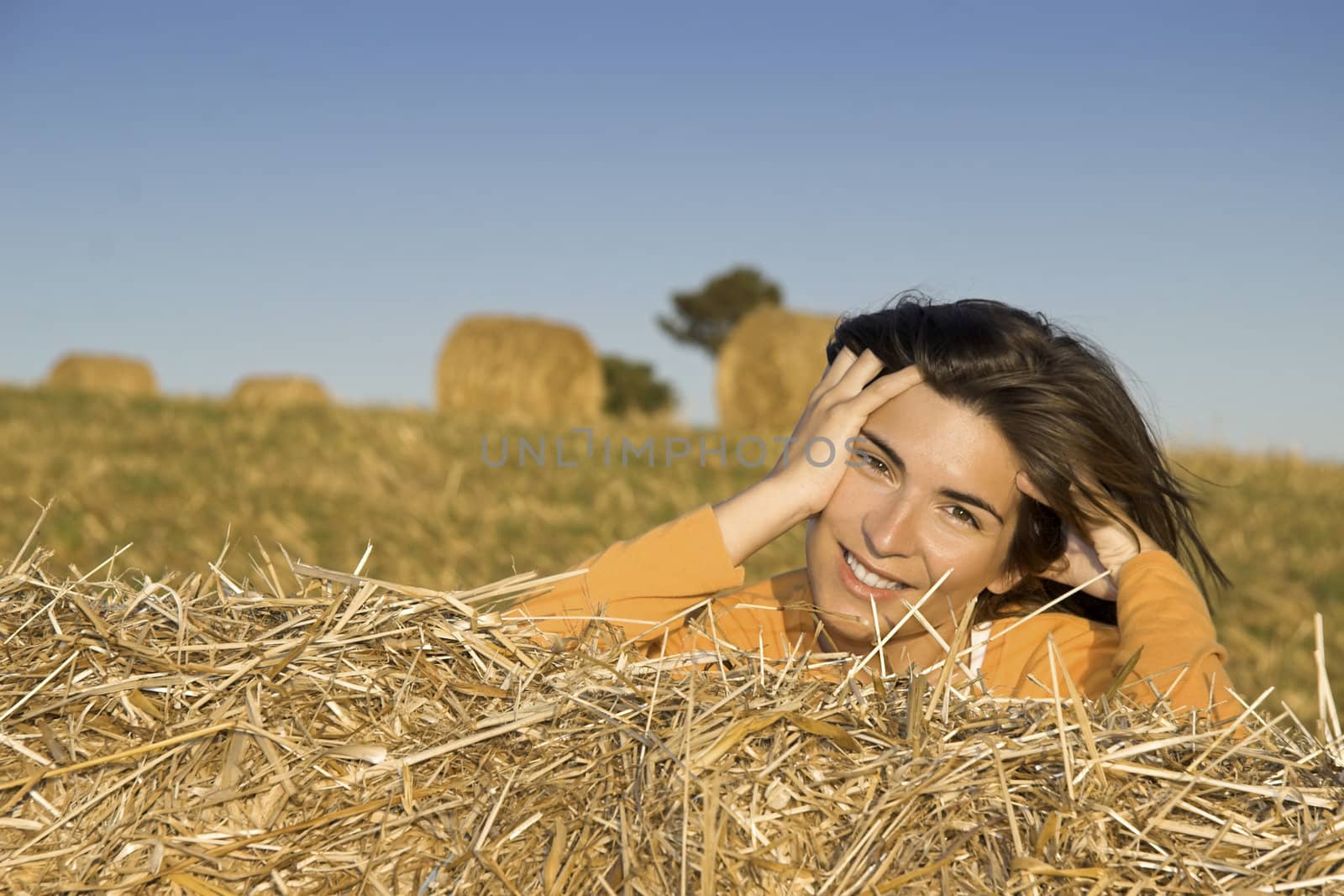 Beautiful woman in a field with hay bales by Iko