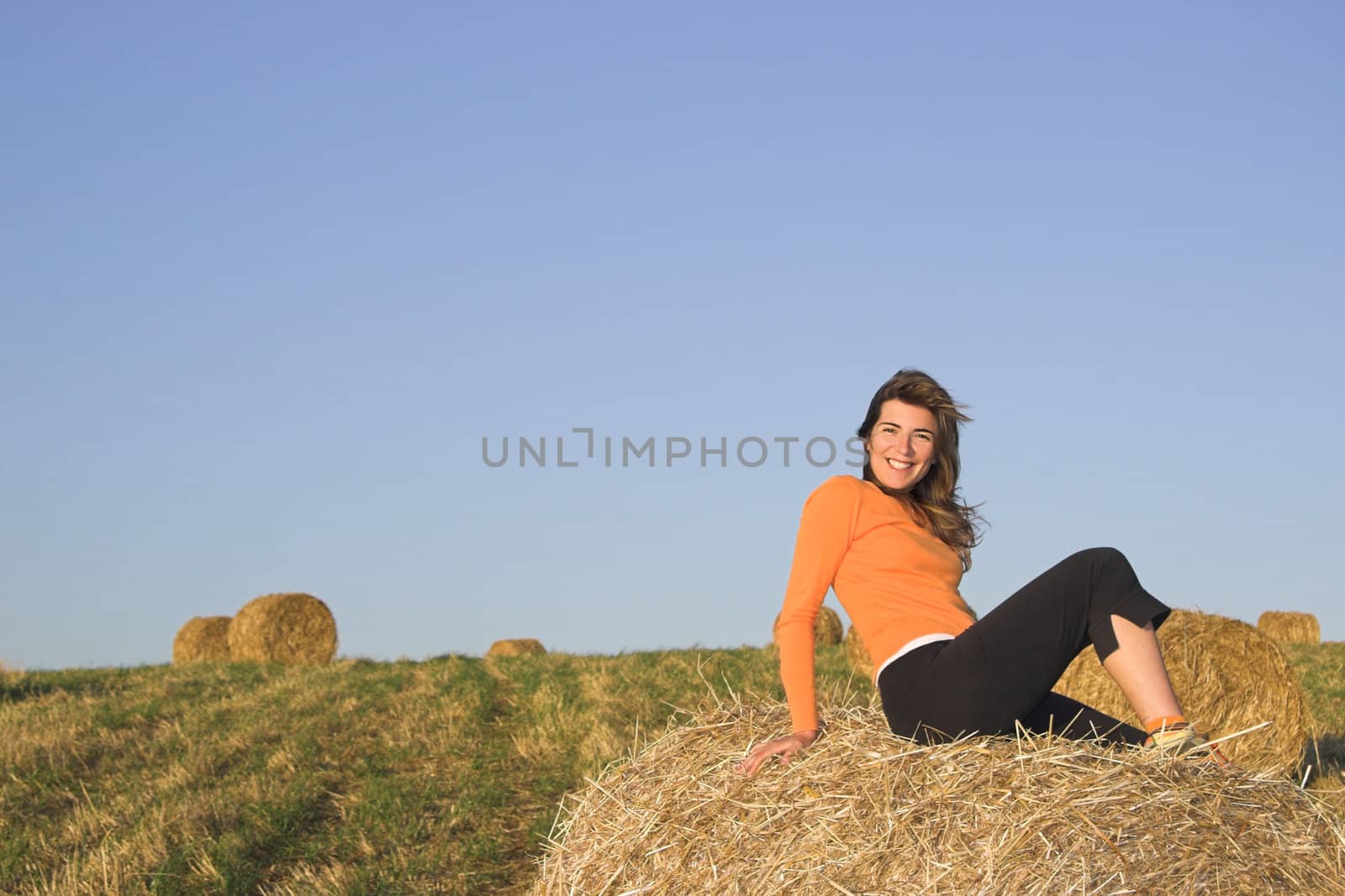 Beautiful woman in a field with hay bales by Iko