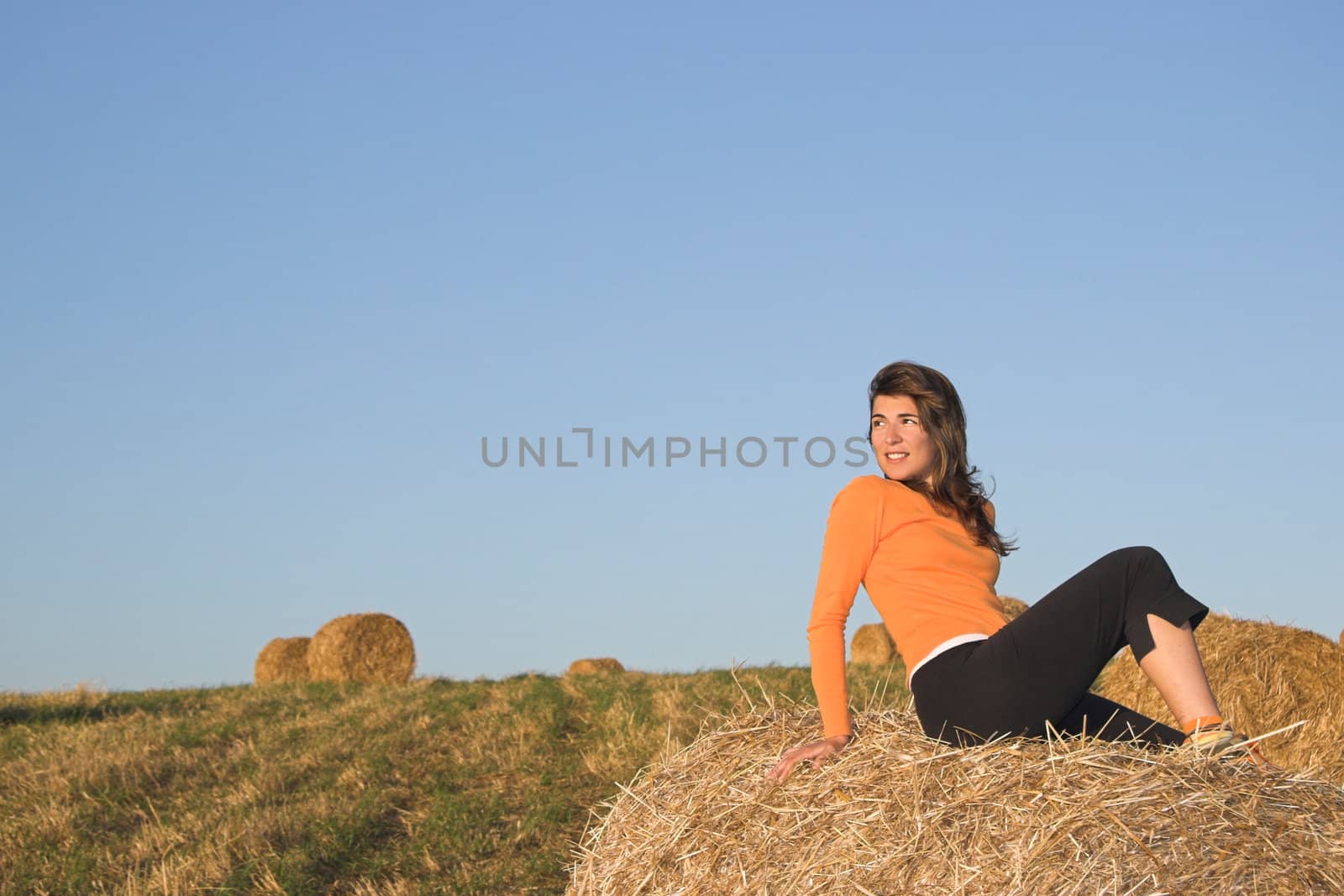 Beautiful woman in a field with hay bales