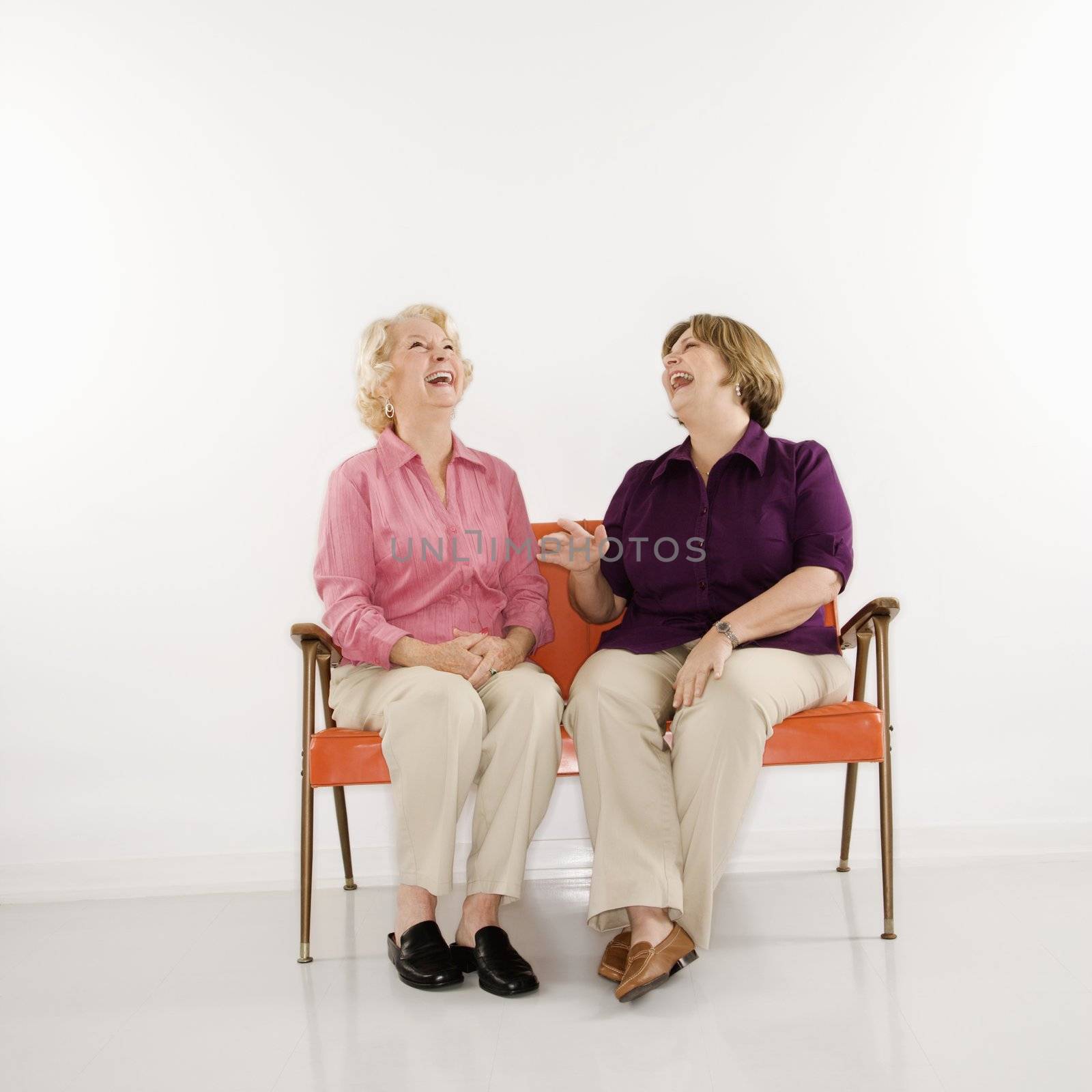 Women sitting laughing. by iofoto